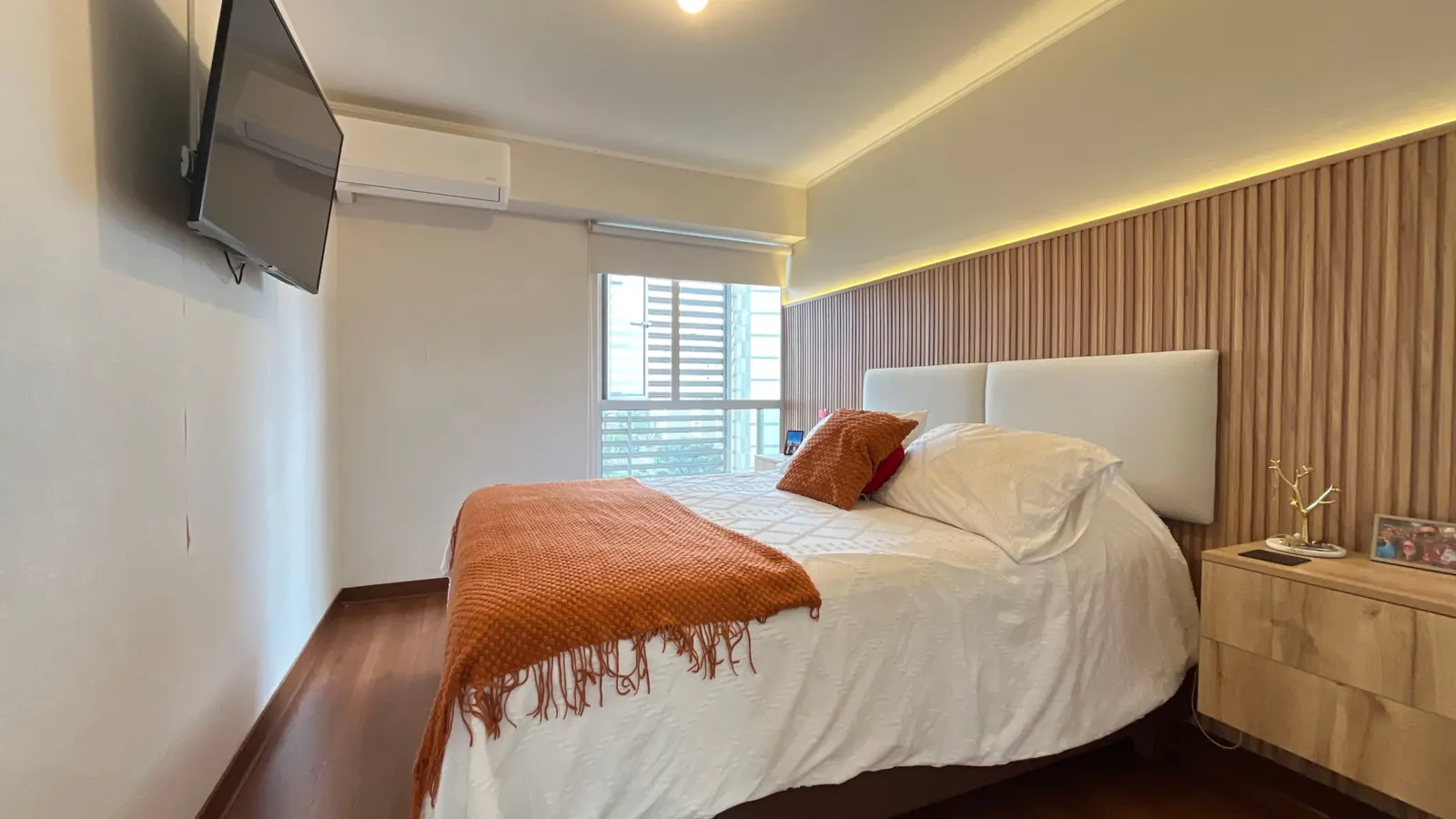 Dormitorio principal con panel de madera e iluminación cálida