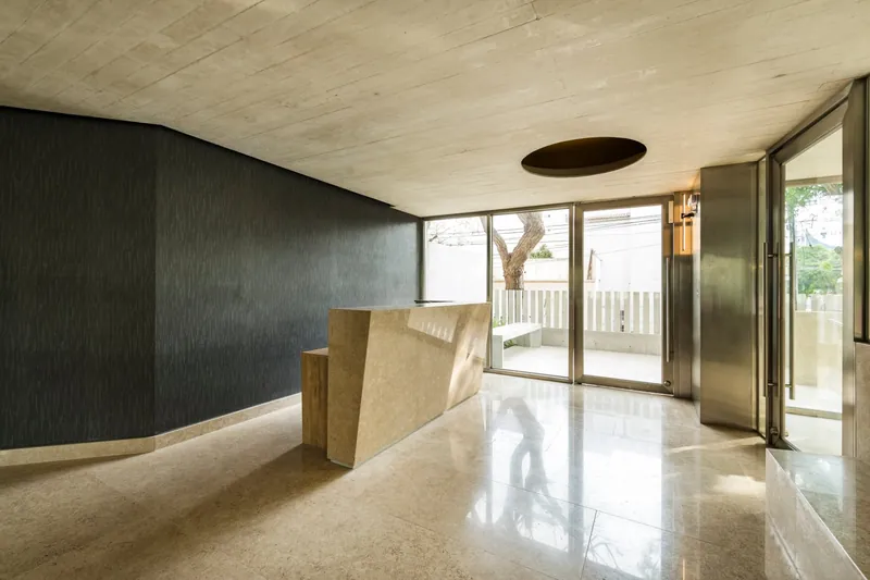 Lobby del edificio con concreto expuesto y mármol